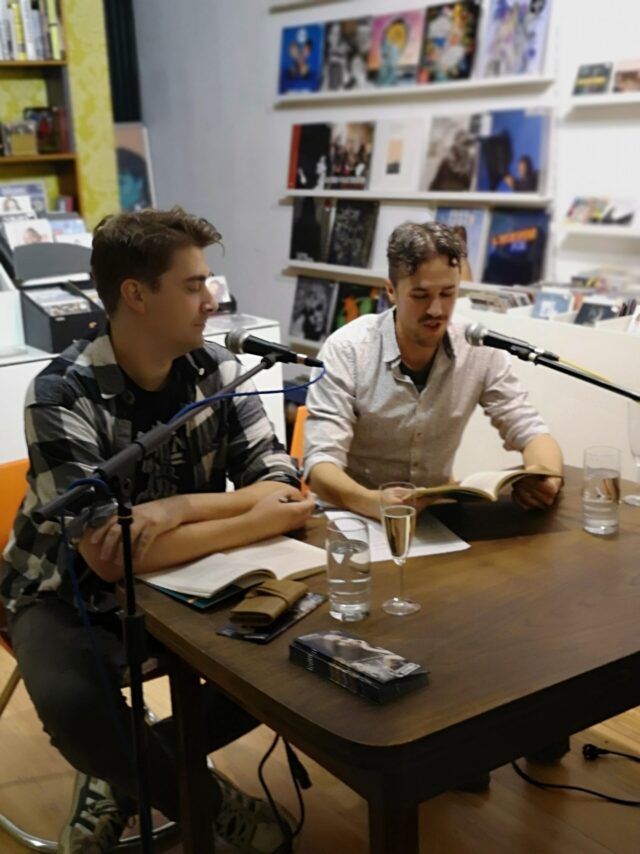 Björn Bischoff & Philip Krömer lesen an einem Tisch bei Bongartz im Lade